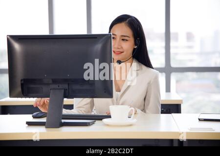 Die asiatische Callcenter-Betreiberin konzentriert sich auf ihre Arbeit im Personal Computer. Konzept für Kundenservice, Lifestyle im Büro, Mitarbeiter. Stockfoto