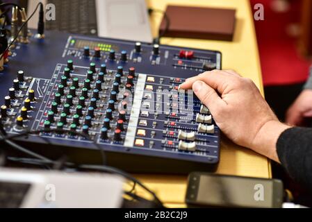 Die menschliche Hand steuert das Bedienfeld des Musikmixers. Stockfoto