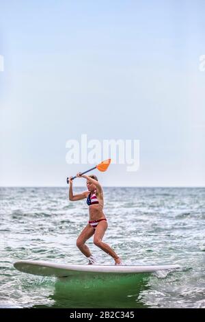 Rentner halten sich aktiv fit beim Paddeln und Surfen und reiten auf einer Welle in der Nähe des Strandes in Neapel Florida. Strandleben genießen. Stockfoto