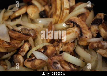 Sautieren Champignons und Zwiebeln in einer Pfanne mit Öl, Gewürze, und Dampf Stockfoto