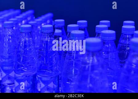 Flaschen mit sauberem Trinkwasser auf blauem Grund. Stockfoto