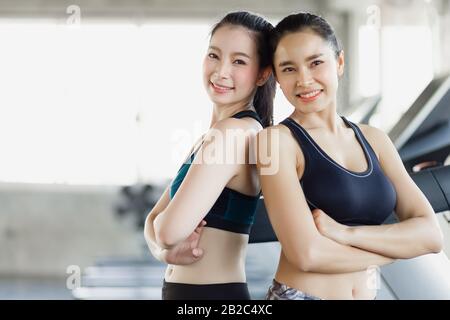 Gruppe attraktive asiatische Frau, die sich die Muskeln ausdehnt und sich nach dem Training, Workout, Fitness im Fitnessclub entspannt. Sport Erholung froh lächelnde Mädchen ist Stockfoto