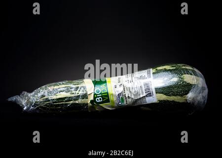 Organisch angebaute Zucchini mit gelbem und grünem Muster, die in Kunststoff eingewickelt und beschriftet sind. ÜBERSETZUNGSETIKETT: "BIO ZUCCHINI" Stockfoto