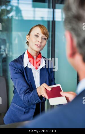 Passagier-Service-Mitarbeiter, der Geschäftsmannspass und Bordkarte im Check-in-Bereich am Flughafen mitgibt Stockfoto