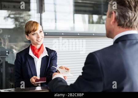 Passagier-Service-Mitarbeiter, der Geschäftsmannspass und Bordkarte im Check-in-Bereich am Flughafen mitgibt Stockfoto