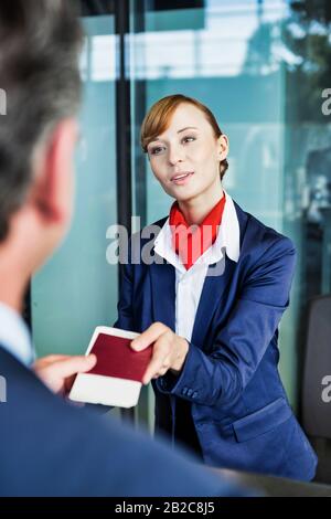 Passagier-Service-Mitarbeiter, der Geschäftsmannspass und Bordkarte im Check-in-Bereich am Flughafen mitgibt Stockfoto