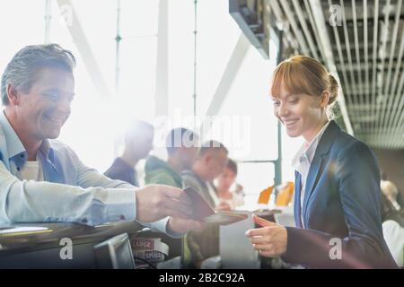 Porträt des Mannes, der seinen Reisepass zum Einchecken mit dem Passagier-Servicemitarbeiter am Flughafen ausgibt Stockfoto