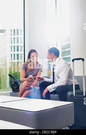 Geschäftspaar spricht während der Sitzung und des Wartens im Empfangsbereich des Hotels Stockfoto