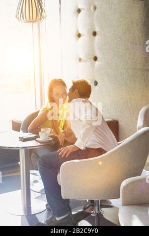 Porträt Des Geschäftsmannes, der seine Freundin im Café sitzend und flüstert Stockfoto