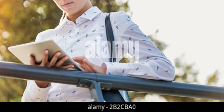 Portrait junger attraktiver Geschäftsfrau mit digitalem Tablet, während sie sich auf Geländer stützt Stockfoto