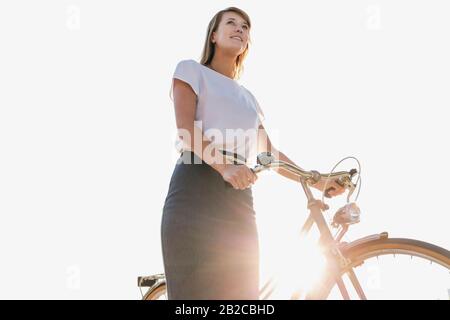 Porträt der jungen attraktiven Geschäftsfrau, die beim Strandspaziergehen Fahrrad hält Stockfoto