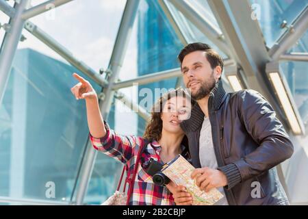 Porträt eines jungen attraktiven Paares, das mitten in der Stadt auf die Karte blickt Stockfoto