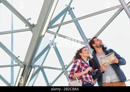 Porträt eines jungen attraktiven Paares, das mitten in der Stadt auf die Karte blickt Stockfoto