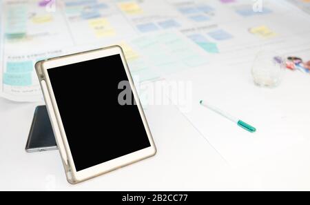 Leeres Bildschirmtablett auf der Besprechungskarte mit vielen Haftnotizideen beim Brainstorming im Geschäftstreffen mit selektivem Fokus, Konzept Stockfoto