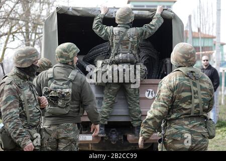 Orestiada, Griechenland. März 2020. Griechische Soldaten tragen am 2. März militärische Ausrüstung zur Reparatur des Zauns nach Krawallen am geschlossenen Grenzübergang Kastanies im Nordosten Griechenlands, wo sich Flüchtlinge und Migranten auf der Grenzlinie zwischen Griechenland und der Türkei von türkischer Seite in der Nähe des Flusses Evros versammelten, um nach Griechenland zu übertreten. 2020. Griechenland hat am Sonntag beschlossen, das Maß der Abschreckung an seinen Grenzen auf das Maximum zu erhöhen, da das Land vor kurzem mit einem bevorstehenden verstärkten Zustrom von Flüchtlingen und Migranten konfrontiert wird. Credit: Dimitris Tosidis/Xinhua/Alamy Live News Stockfoto