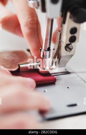 Ein Lederhandwerker stellt in seinem Laden Lederwaren an einer Nähmaschine her. Handgefertigte Arbeit. Nahaufnahme. Stockfoto