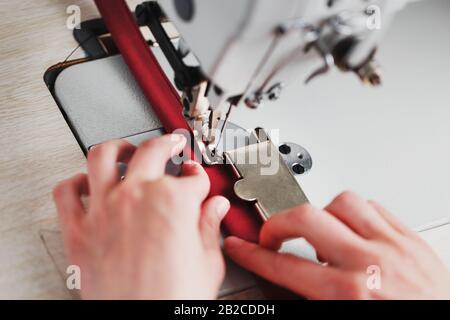 Ein Lederhandwerker stellt in seinem Laden Lederwaren an einer Nähmaschine her. Handgefertigte Arbeit. Nahaufnahme. Stockfoto