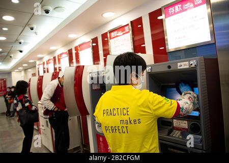 Macao, China. März 2020. Ein Mitarbeiter desinfiziert die Geldeinlagenmaschine in einer Filiale der Bank of China in Macao, Südchina, am 2. März 2020. Credit: Cheong Kam Ka/Xinhua/Alamy Live News Stockfoto