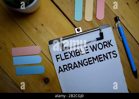 Flexible Arbeitsvereinbarungen schreiben auf einem Papier, der isoliert auf Holzhintergrund liegt. Stockfoto