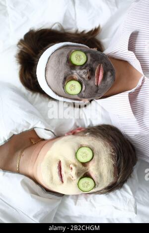 Mann und Frau legen Gesichtsmaske und Gurken an Stockfoto