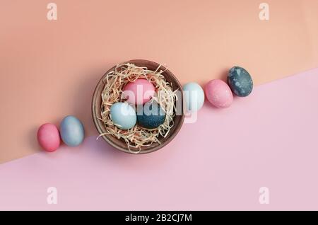 Heller ostergruss mit gefärbten bunten Hühnereiern auf Strohhalm auf dem Teller Stockfoto