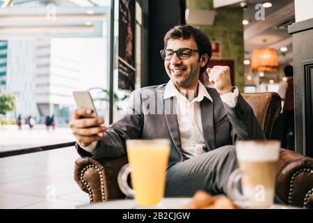 Ein glücklicher Geschäftsmann, der in einer Bar frühstücken kann Stockfoto