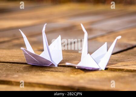 Zwei Origami-Kräne auf Holzhintergrund. Symbol für Frieden und Hoffnung. Stockfoto