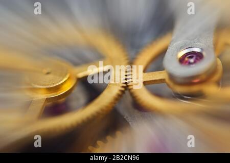 Metall-Zahnräder im Uhrwerk, abstrakte Sonnenstrahlen, Konzeptbewegung ist Leben, Teamarbeit, Ideentechnik, Unendlichkeit. Makro. Stockfoto