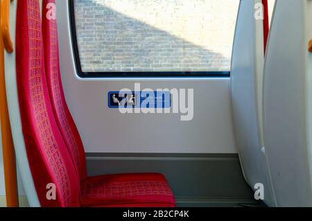 Nahaufnahme eines leeren Zugsitzes mit einem Schild mit der Aufschrift „bevorzugte Sitzplätze für ältere Menschen und alle, die sie benötigen könnten“, London England, Großbritannien Stockfoto