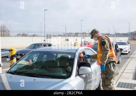 Ein US-Soldat beatmelt Passagiere für COVID-19 mit einem Thermometer an einem Eingangstor für Army Garrison Humphreys, 27. Februar 2020 in Pyeongtaek, Südkorea. Der Ausbruch des neuartigen Coronavirus in Südkorea ist an zweiter Stelle nur für China. Stockfoto