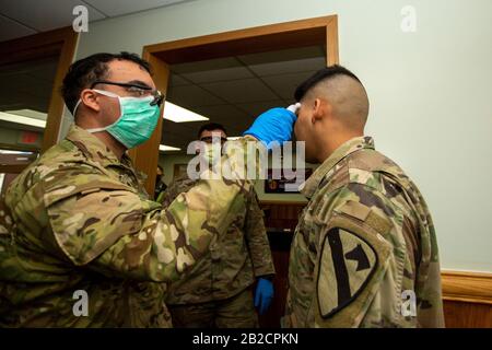 Ein Sanitäter der US-Armee stellt einen Mitsoldaten für COVID-19 unter Verwendung eines Thermometers am Eingang der Army Garrison Casey vom 26. Februar 2020 in Dongducheon, Südkorea, auf. Der Ausbruch des neuartigen Coronavirus in Südkorea ist an zweiter Stelle nur für China. Stockfoto