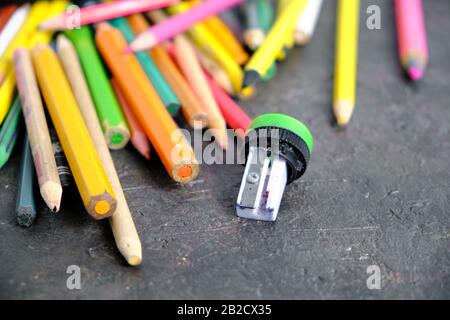 Alte Buntstifte und ein gebrochener Bleistiftspitzer auf dem Boden Stockfoto