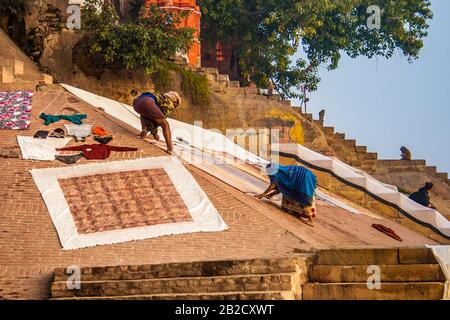 Ein Paar Männer und Frauen hängt Kleidung zum Trocknen in einem offenen Gebiet in der Nähe des Ganga-Flusses in Varanasi, Indien Stockfoto