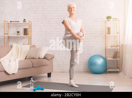 Aktive Seniorin erwärmt sich zu Hause Stockfoto