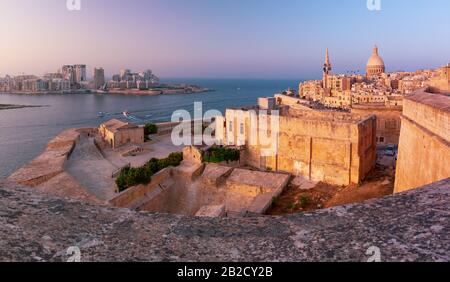 Sliema und Die Altstadt von Valletta mit Festung, Unserer Lieben Frau von der Kirche Mount Carmel und der anglikanischen Pro-Kathedrale St. Paul bei Sonnenuntergang, Hauptstadt von Malta Stockfoto