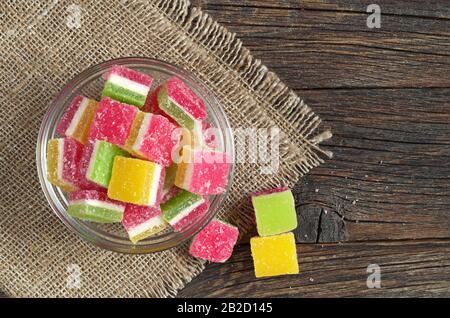 Bunte Gelee Süßigkeiten in einer Glasschale auf dunklem Holzhintergrund, Draufsicht Stockfoto