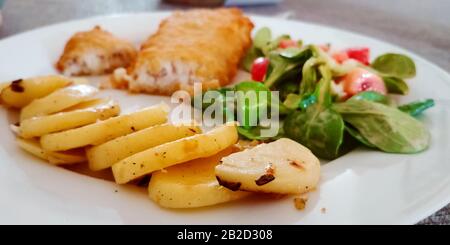 Traditionelle Mahlzeit mit Kartoffeln, frittiertem Fisch und Salat. Selektiver Fokus. Stockfoto