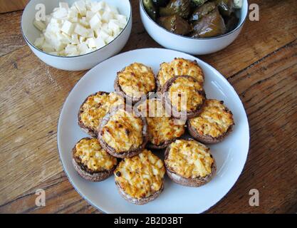 Tisch mit vegetarischer Kost, gefüllten Champignons, Käse und Weinblättern auf Teller Stockfoto