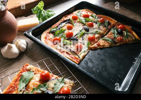 Hausgemachte Pizza mit Eierpflanze, Kirschtomaten, Käse, Oliven und Rakete Stockfoto
