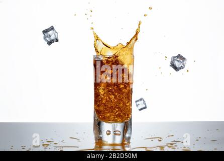 Eiswürfel spritzen in ein Glas Whisky Stockfoto