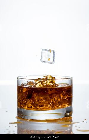 Ein Eiswürfel spritzt in ein Glas Whisky Stockfoto