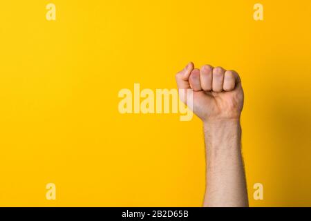 Der Closeup-Mann überhängt einen gelben Hintergrund, Protest und Machtzeichen Stockfoto