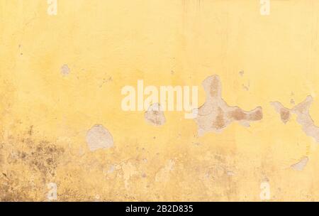 Nahaufnahme einer verwitterten und alten Betonwand, die in Gelb lackierte Pflasterung ist gebrochen. Hochauflösender, abstrakter Vollformatshintergrund. Stockfoto