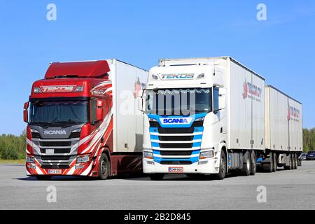 Der rote Scania R500 und der weiße Scania S500 von Tekos Oy vor dem Transportanhänger, der auf einer Lkw-Haltestelle geparkt ist. Jalasjarvi, Finnland. August 2019. Stockfoto