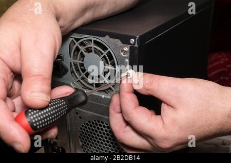 Computerreparatur. Entfernen der Abdeckung der Systemeinheit. Staub auf dem Lüfter, Schäden am Kühlsystem Stockfoto