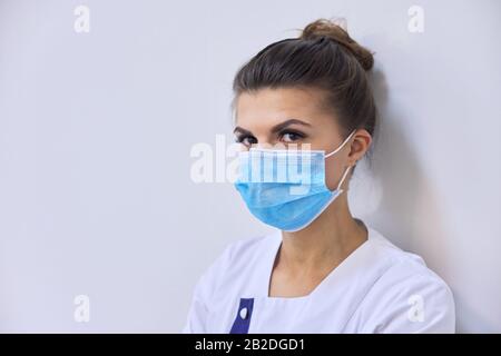 Junge seriöse Frau Doktor in medizinischer Maske mit Blick auf die Kamera Stockfoto