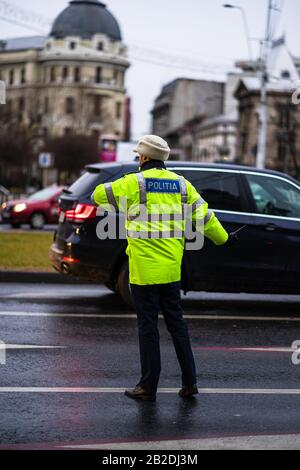 Polizeiagent, rumänische Verkehrspolizei (Politia Rutiera), die den Verkehr während der morgendlichen oder abendlichen Hauptverkehrszeit in der Innenstadt von Bukarest, Rumänien, 2020 lenkt Stockfoto