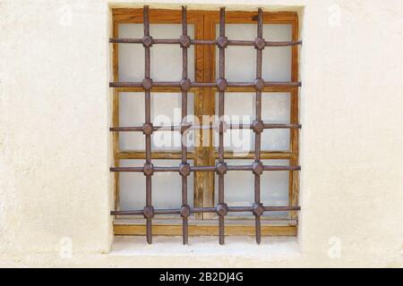 Metallgitter mit geometrischem Muster an einem alten Holzfenster. Architektonisches Schutzelement Stockfoto