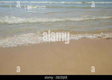 Flauschige Wellen am goldenen Sandstrand. Wunderschönes kristallklares Wasser. Feiner, sauberer Sand. Sonnige tropische Küste am Strand von Patong, der Westküste von Phuket, Thailand Stockfoto