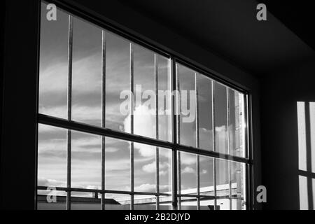 Der Blick von einem gesperrten Fenster auf den blauen Himmel mit weißen Wolken Stockfoto